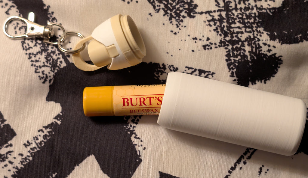 Burt's Bees lip balm and keychain on a patterned fabric background